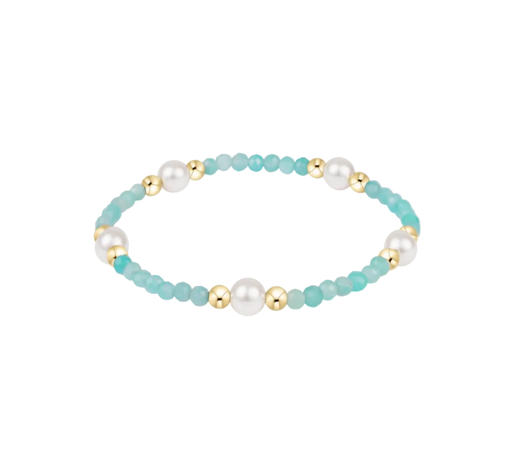 Bracelet with turquoise beads, pearls, and gold accents on a white background