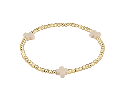 Gold beaded bracelet with beige beads on a white background