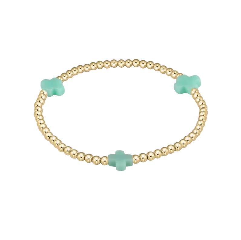 Gold bracelet with turquoise clover-shaped beads on a white background