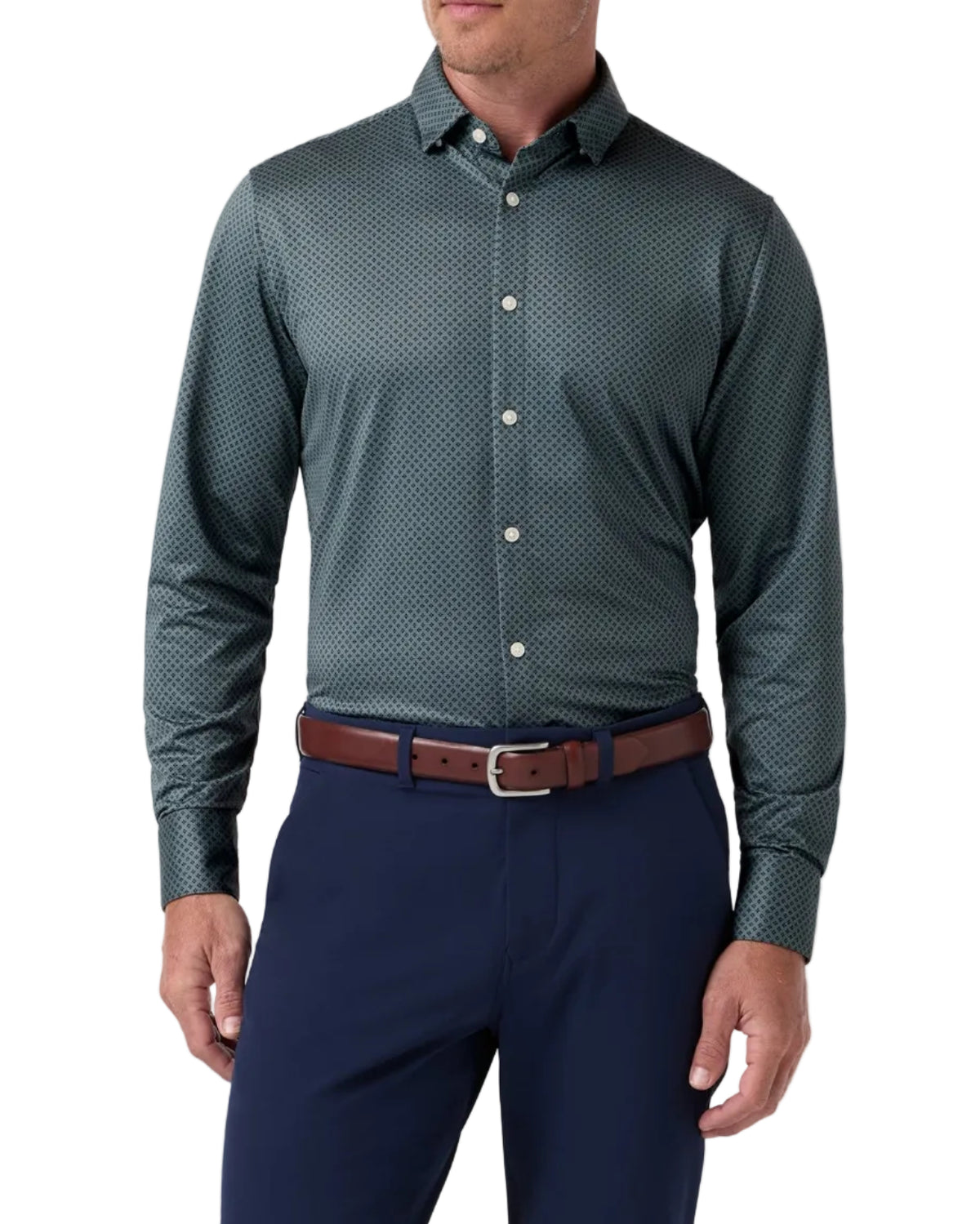 A man wearing a dark green patterned long-sleeve dress shirt with a brown leather belt and navy blue trousers, standing against a light gray studio background.