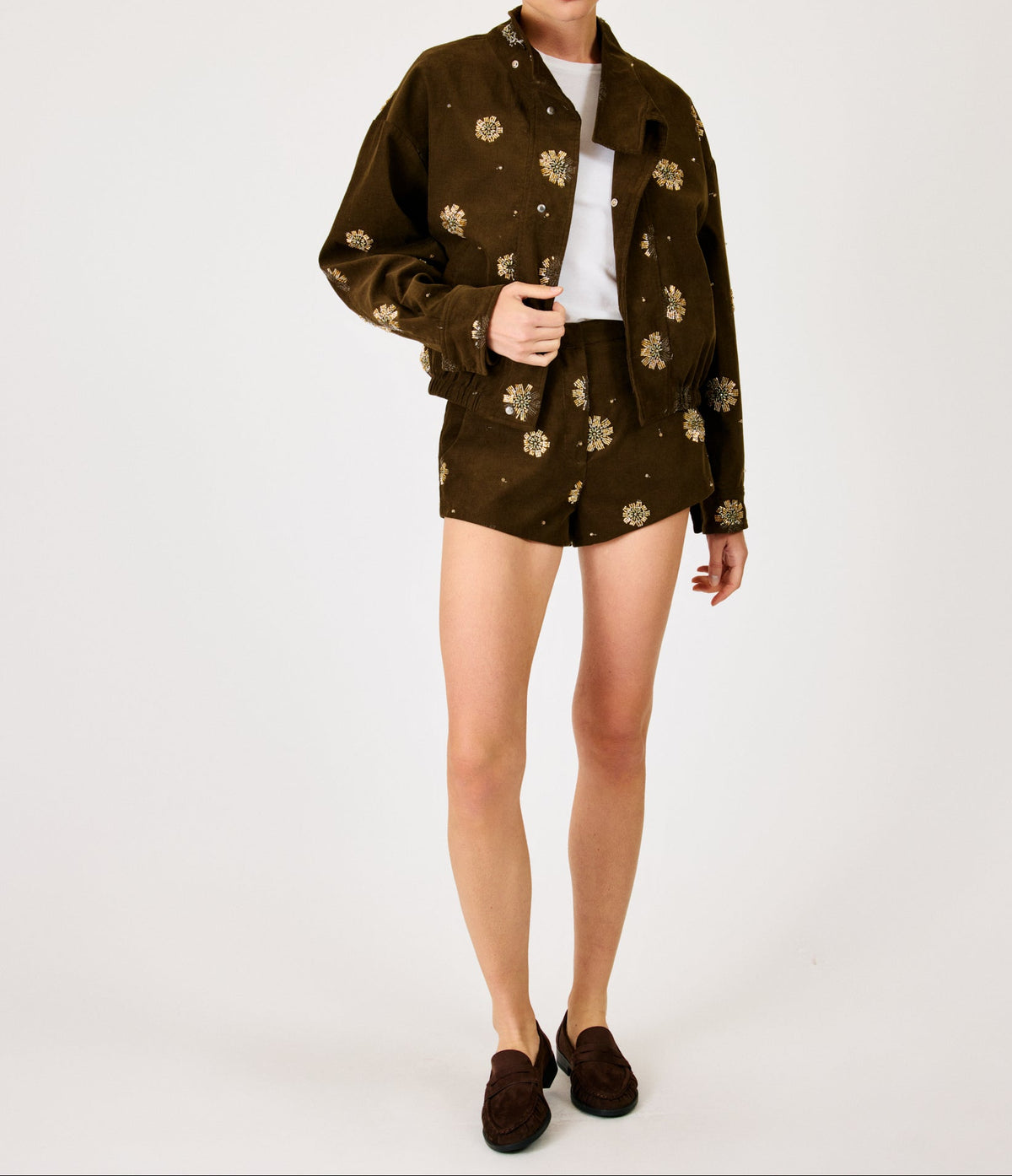 Woman wearing a dark brown floral jacket over a white shirt on a white background